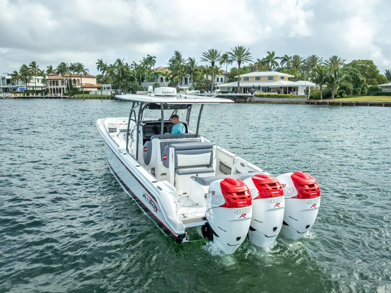 Slide: The Image of 2018 Nor-Tech 390 boat with triple outboard engines cruising on a scenic waterway. - 6