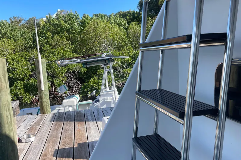 Slide: The Image of 2004 Endeavour Explorer 46 PowerCat with ladder and wooden deck, surrounded by lush greenery. - 28