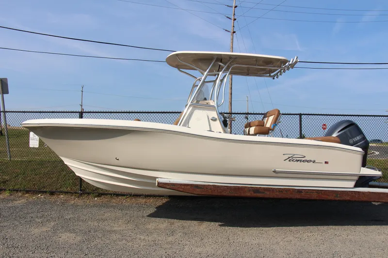 Slide: The Image of 2025 Pioneer 222 Islander boat with Yamaha engine, parked on gravel near a fence. - 9