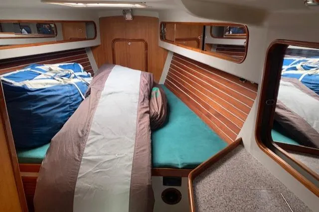 Slide: The Image of 1996 Santa Cruz 52 yacht interior cabin with wooden paneling and cozy bedding. - 18