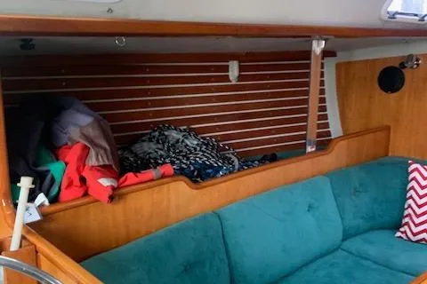 Slide: The Image of Interior of a 1996 Santa Cruz 52 sailboat with teal seating and wooden paneling. - 19