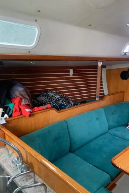 Slide: The Image of Interior of a 1996 Santa Cruz 52 sailboat with teal seating and wooden accents. - 30