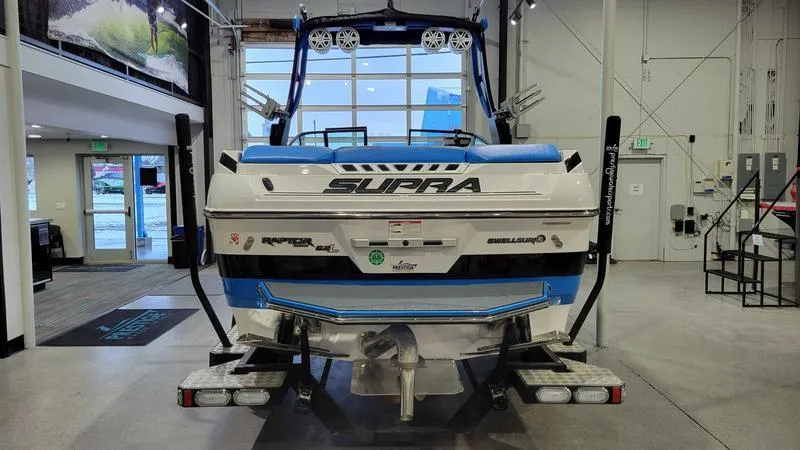 Slide: The Image of 2018 Supra SL 450 boat in showroom, rear view with blue and white design. - 6