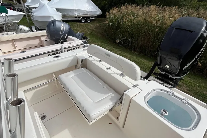 Slide: The Image of 2012 Cobia 237CC boat interior with seating and motor, surrounded by greenery and covered boats. - 16