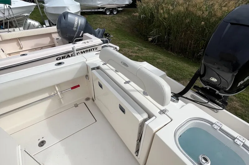 Slide: The Image of 2012 Cobia 237CC boat interior with seating and motor, parked outdoors. - 17