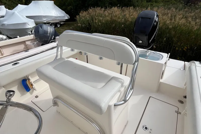 Slide: The Image of 2012 Cobia 237CC boat interior with white seating and motor. - 18