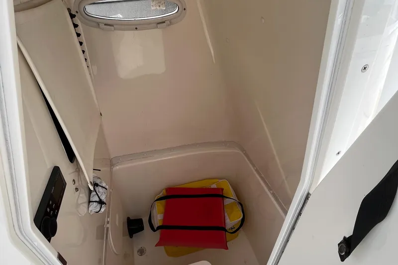 Slide: The Image of 2012 Cobia 237CC boat interior storage compartment with window and safety equipment. - 27