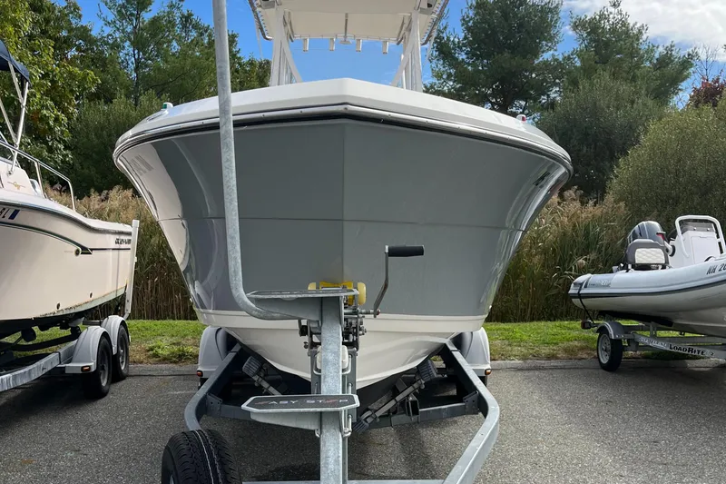 Slide: The Image of 2012 Cobia 237CC boat on trailer, parked between other boats, front view. - 3