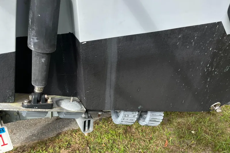 Slide: The Image of Close-up of a 2012 Cobia 237CC boat's hull and trailer on grass. - 6