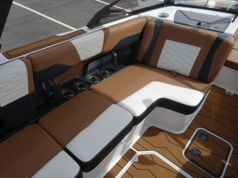 Slide: The Image of 2025 Malibu 24 MXZ interior with brown and white seating, cup holders, and sleek design. - 11