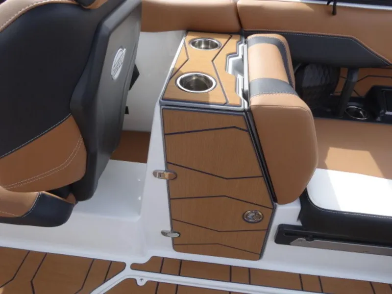 Slide: The Image of 2025 Malibu 24 MXZ boat interior with tan and black seating, featuring cup holders. - 14