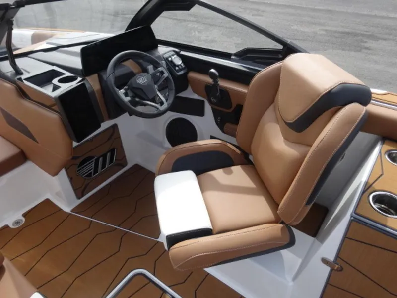 Slide: The Image of 2025 Malibu 24 MXZ boat interior with tan and black seating, modern dashboard, and cup holders. - 15