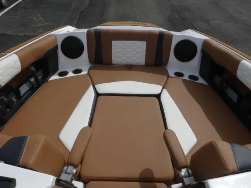Slide: The Image of 2025 Malibu 24 MXZ boat interior with brown and white seating, cup holders, and speakers. - 18