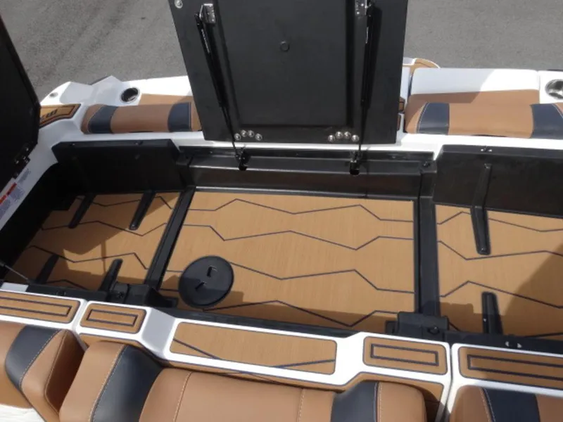 Slide: The Image of 2025 Malibu 24 MXZ boat interior storage compartment with brown and black seating. - 5