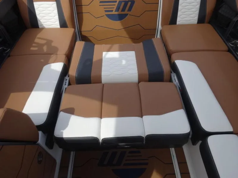 Slide: The Image of 2025 Malibu 24 MXZ boat interior with brown and white cushioned seating. - 8