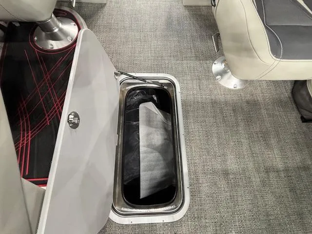 Slide: The Image of 2025 Barletta CORSA 23QC boat interior storage compartment with open hatch on carpeted floor. - 7