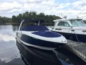 Slide: The Image of 2012 Regal 2700 Bowrider boat docked on a calm lake with trees in the background. - 2