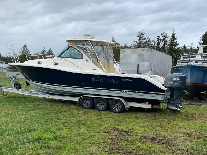 The Image of 2007 Pursuit OS 335 boat on trailer, parked on grass, with Yamaha outboard motor. - 0