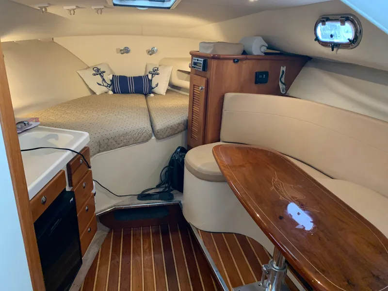 Slide: The Image of 2007 Pursuit OS 335 cabin interior with cozy seating, wooden table, and compact kitchen area. - 13