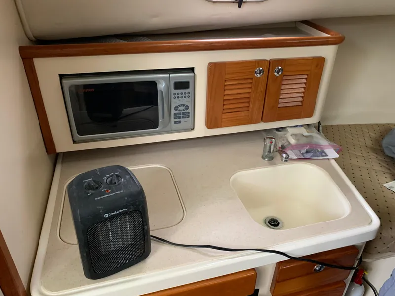 Slide: The Image of 2007 Pursuit OS 335 boat kitchenette with microwave, sink, and heater. - 16