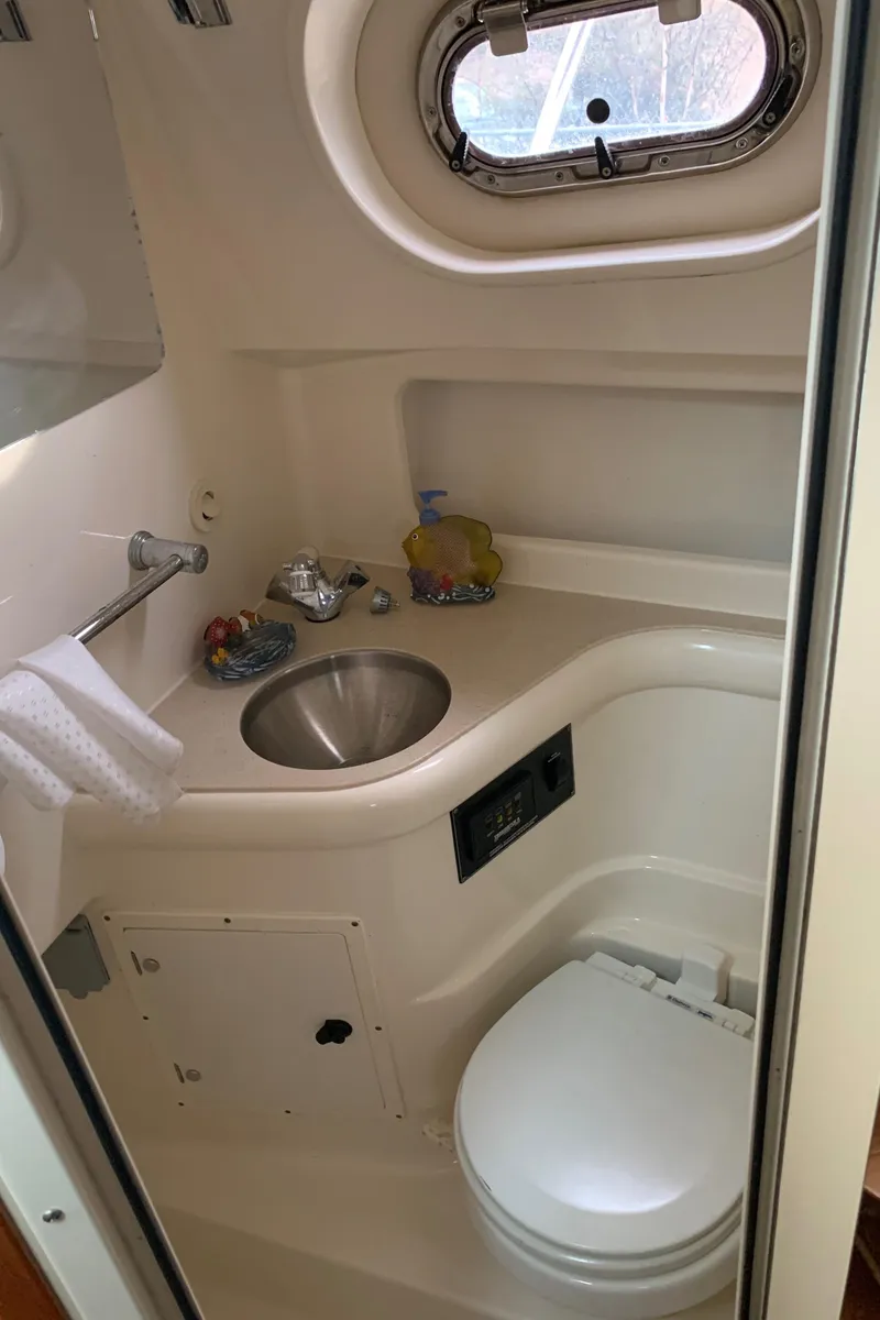Slide: The Image of 2007 Pursuit OS 335 boat bathroom with sink, toilet, and porthole window. - 22