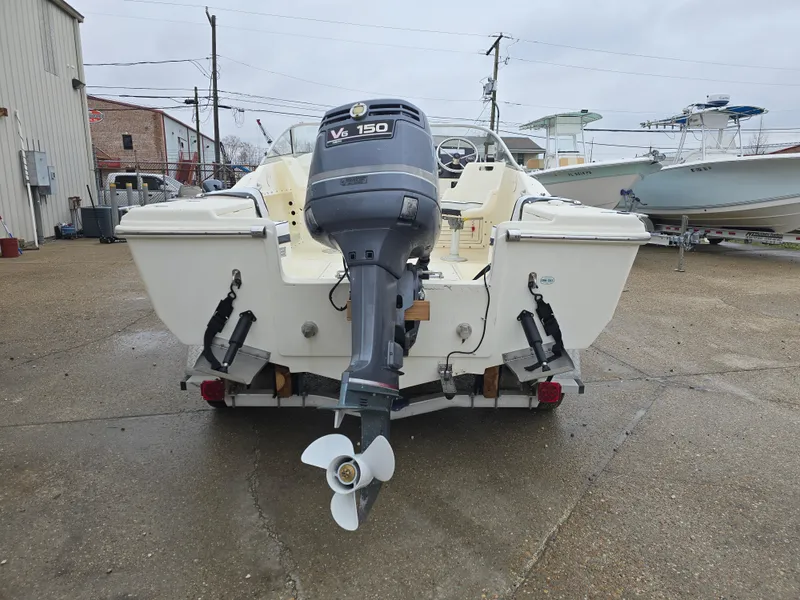 Slide: The Image of 2003 Scout 202 Dorado boat with V6 150 outboard motor, parked outdoors. - 3
