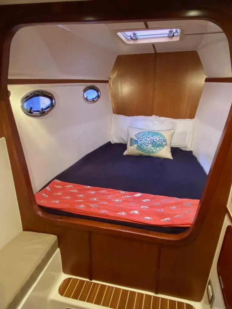 Slide: The Image of 2013 Africat PowerCat Sportfisher cabin interior with cozy bed and porthole windows. - 39