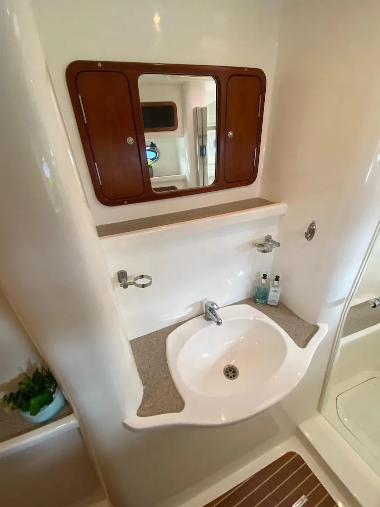 Slide: The Image of 2013 Africat Marine PowerCat Sportfisher bathroom with sink, mirror, and storage cabinet. - 49