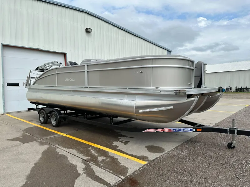 The Image of 2025 Barletta Aria 24UC pontoon boat on trailer outside a warehouse. - 1