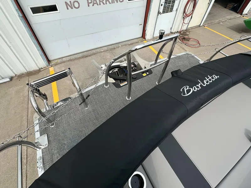 Slide: The Image of 2025 Barletta Aria 24UC boat deck with railing and cover, near a "No Parking" sign. - 24