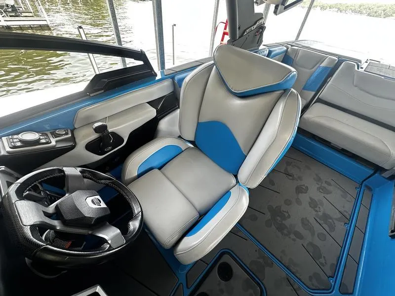 Slide: The Image of 2021 Malibu M220 boat interior with blue and gray seating, steering wheel, and control panel. - 11
