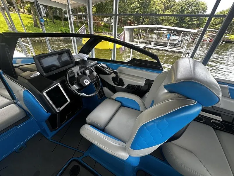 Slide: The Image of 2021 Malibu M220 boat interior with blue and gray seating, modern dashboard, and steering wheel. - 13