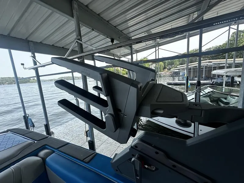 Slide: The Image of 2021 Malibu M220 boat in dock, featuring wakeboard rack and lake view. - 15