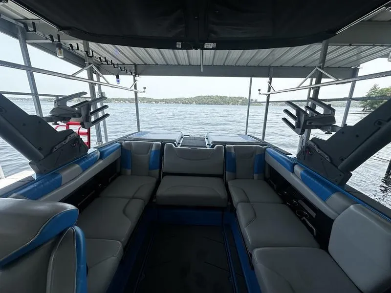 Slide: The Image of Interior of 2021 Malibu M220 boat with spacious seating, docked by a serene lake. - 17