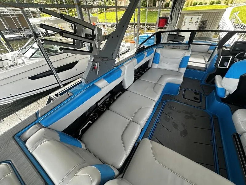 Slide: The Image of 2021 Malibu M220 boat interior with blue and gray seating, docked at marina. - 19