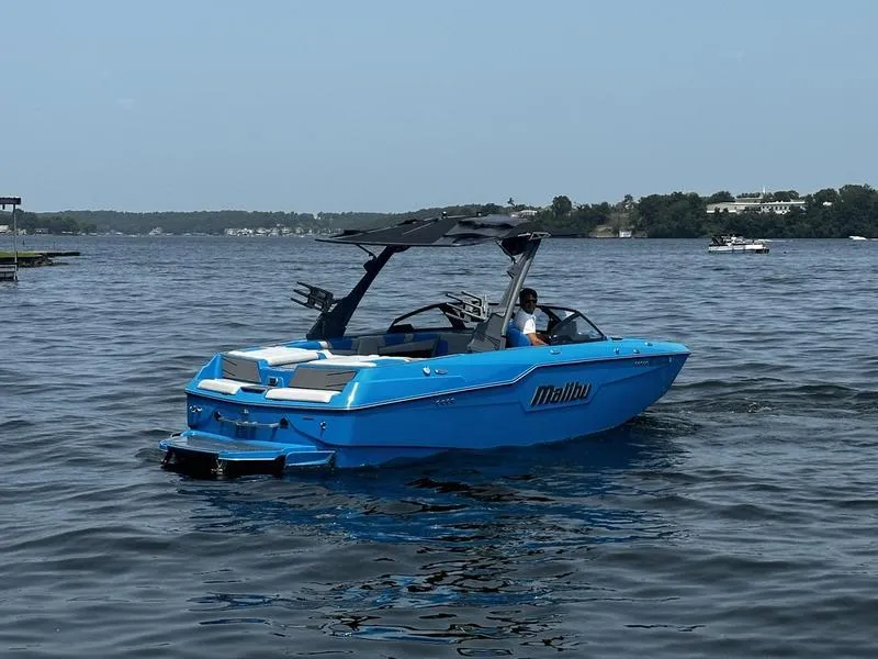 Slide: The Image of 2021 Malibu M220 boat in blue on a calm lake. - 3