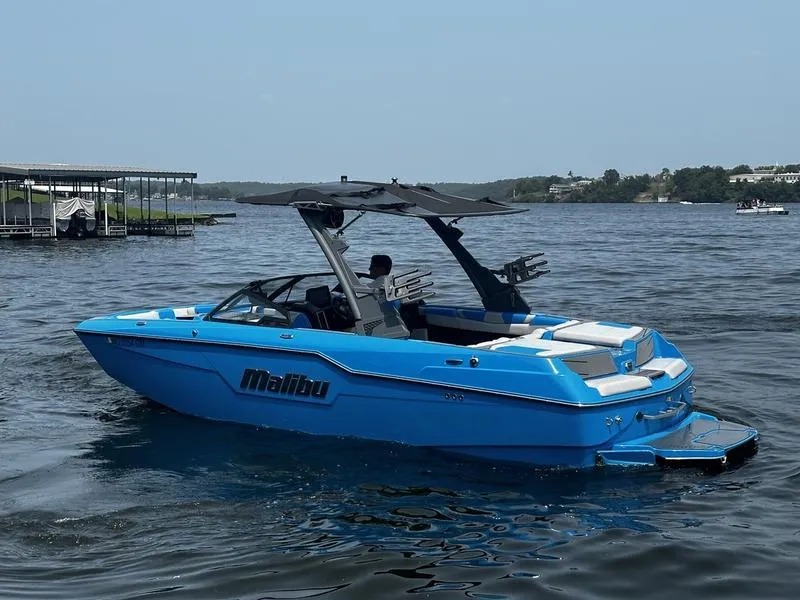 Slide: The Image of Blue 2021 Malibu M220 boat on a lake, featuring sleek design and modern amenities. - 5