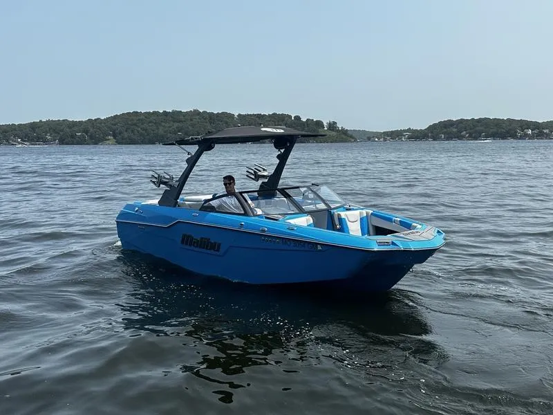Slide: The Image of 2021 Malibu M220 boat on a lake, with a person at the helm. - 8