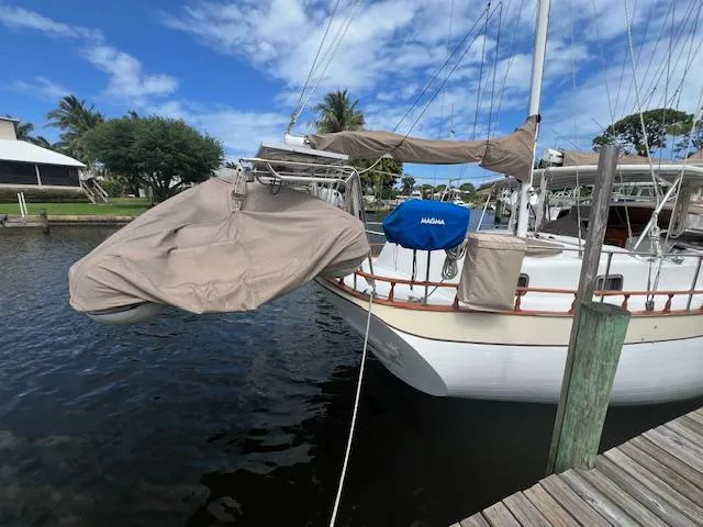 Slide: The Image of 1981 Hardin Voyager 45 Ketch docked, covered equipment, blue sky, calm water. - 12
