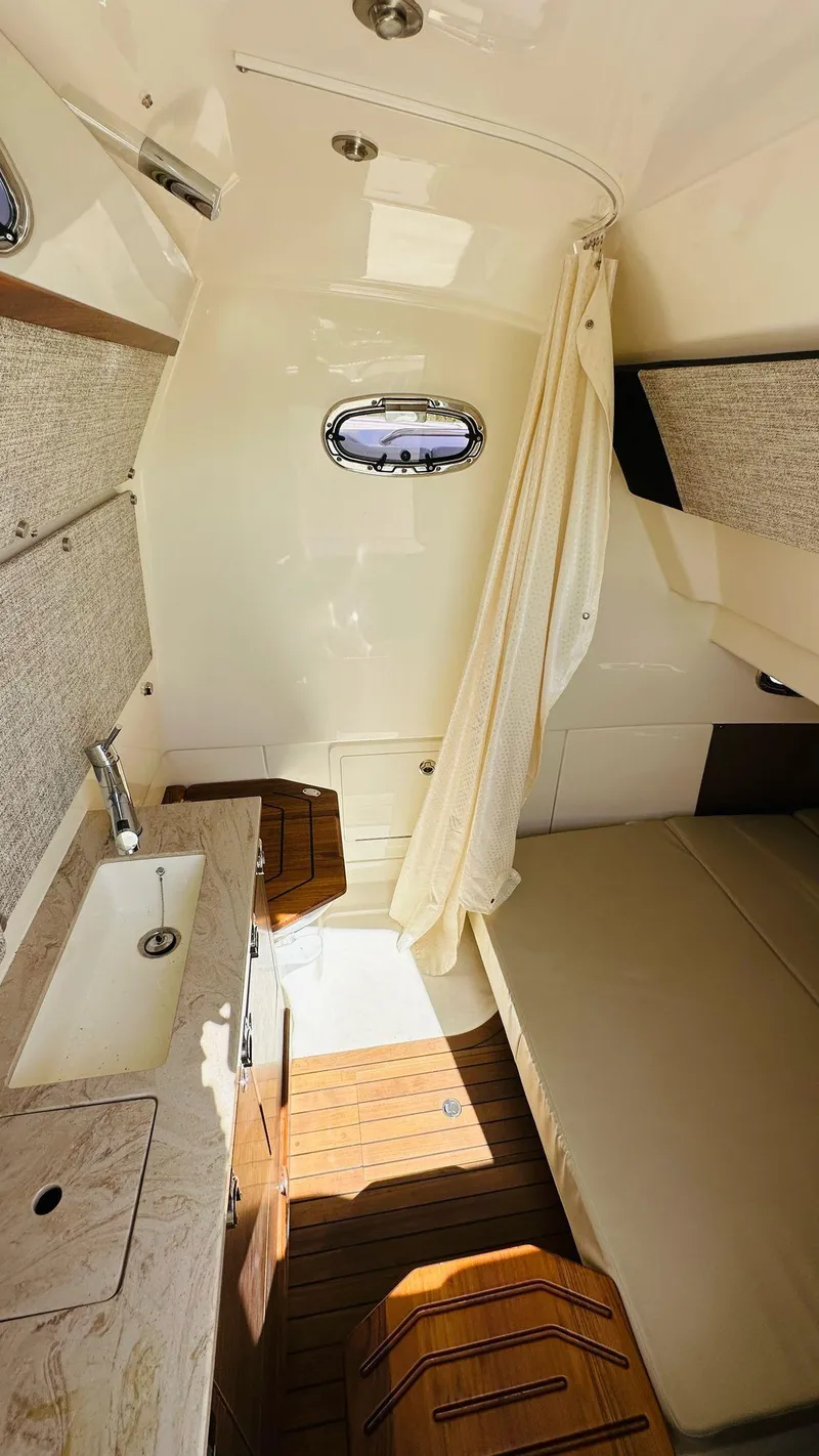 Slide: The Image of 2023 Boston Whaler 360 Outrage cabin interior with sink, bed, and wooden flooring. - 6