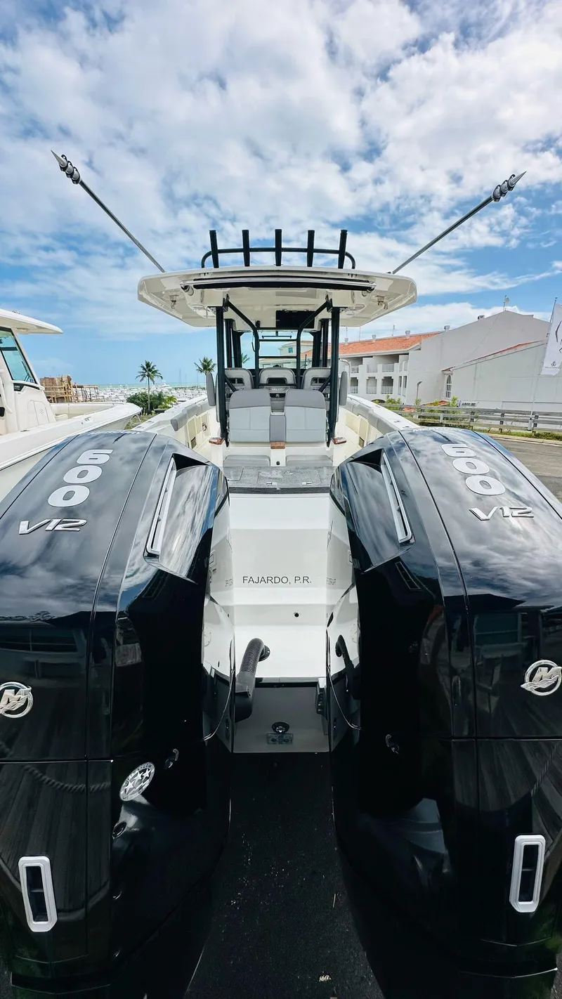 Slide: The Image of 2023 Boston Whaler 360 Outrage boat with dual engines, docked under a partly cloudy sky. - 7
