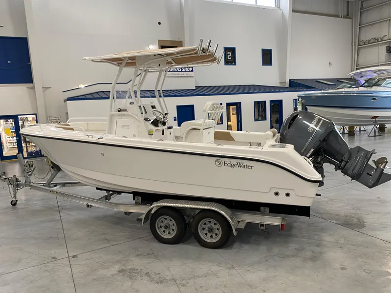 Slide: The Image of 2023 Edgewater 208CC boat on trailer in showroom, featuring outboard motor. - 0