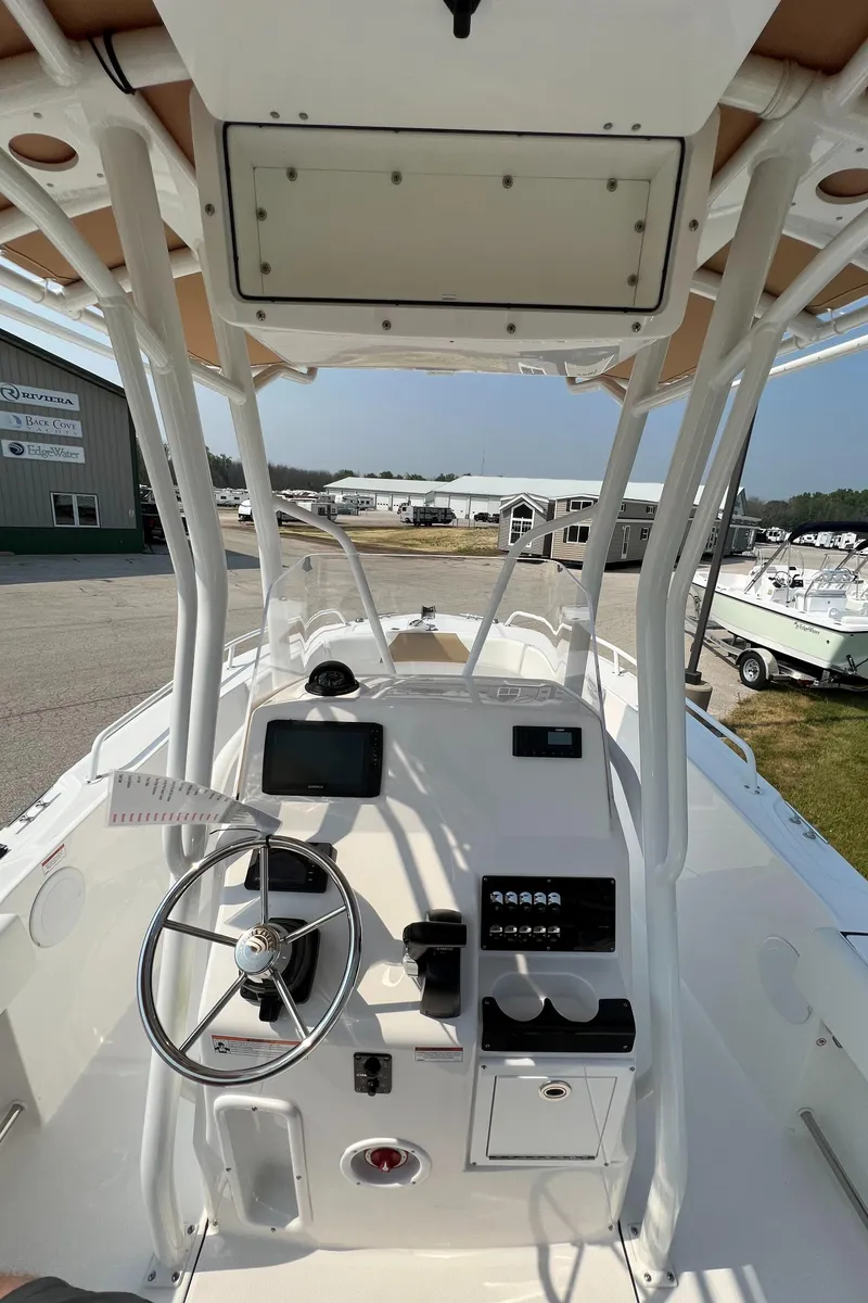 Slide: The Image of 2023 Edgewater 208CC boat console with steering wheel and controls, docked outdoors. - 19