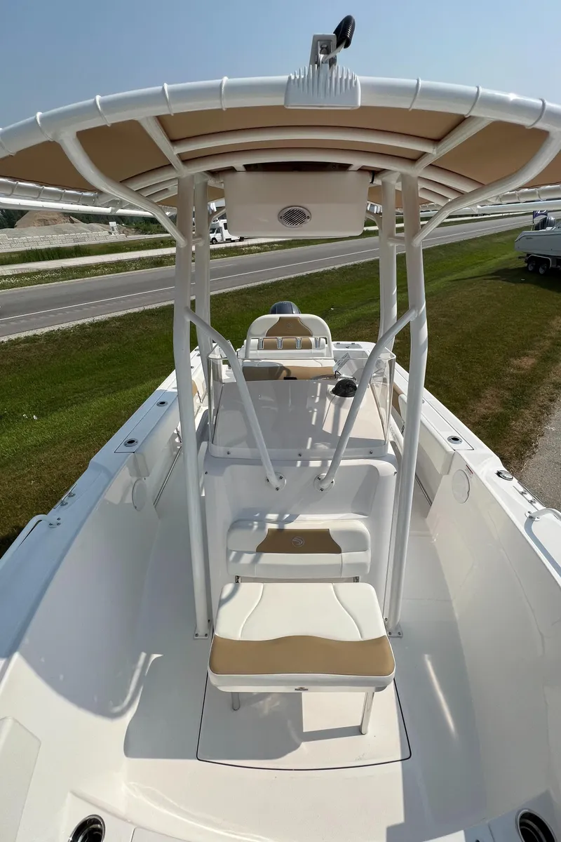 Slide: The Image of 2023 Edgewater 208CC boat with T-top, beige seating, and open deck design. - 25