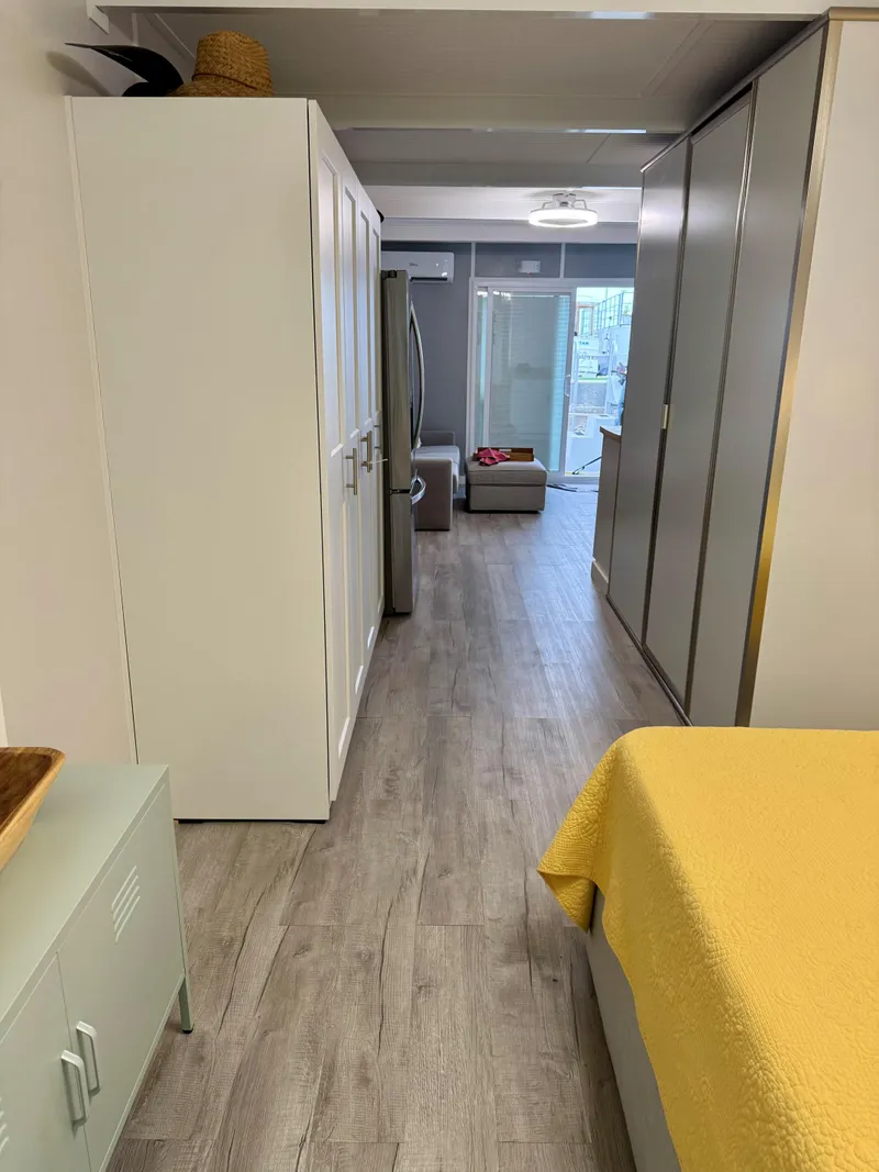 Slide: The Image of Modern apartment interior with wooden flooring, yellow bedding, and sleek storage units, 2023 design. - 15