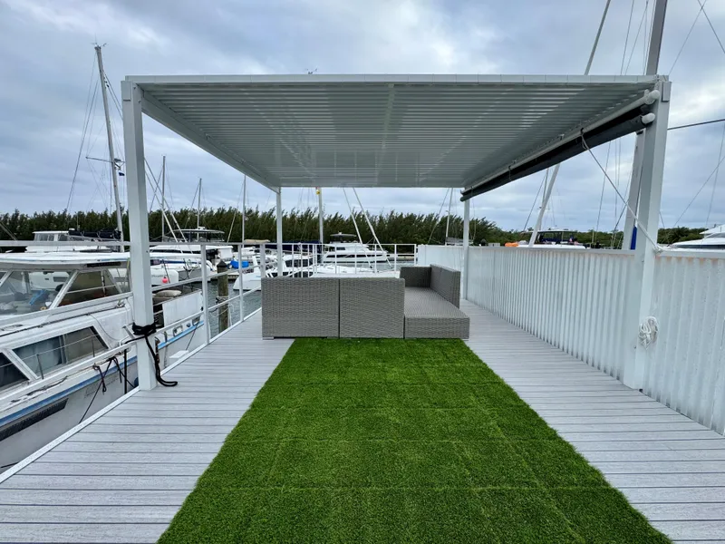 Slide: The Image of Modern Struktures MS 400 patio with pergola, artificial grass, and outdoor seating by marina. - 22