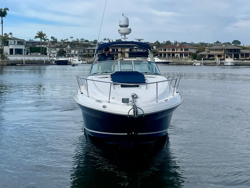 Slide: The Image of 2006 Sea Ray 320 Sundancer yacht on calm water, with waterfront homes in the background. - 1