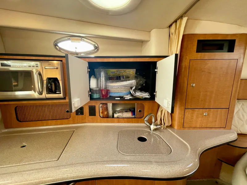 Slide: The Image of 2006 Sea Ray 320 Sundancer kitchen with microwave, sink, and open cabinets. - 19
