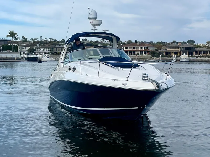 Slide: The Image of 2006 Sea Ray 320 Sundancer yacht on calm water, with waterfront homes in the background. - 3