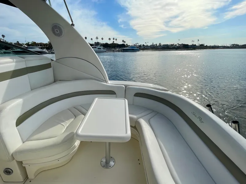 Slide: The Image of 2006 Sea Ray 320 Sundancer boat with white seating and table, overlooking calm waters. - 31
